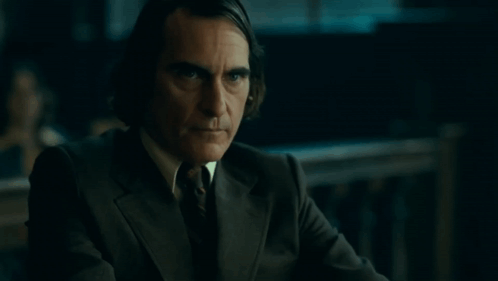 a man in a suit and tie is looking at the camera .