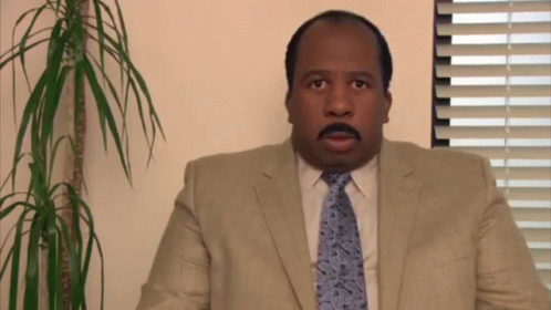 A Man In A Suit And Tie Is Looking At The Camera GIF