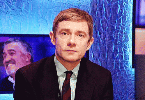 A Man In A Suit And Tie Is Looking At The Camera GIF