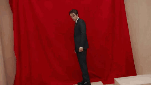 A Man In A Suit And Tie Is Looking At The Camera . GIF