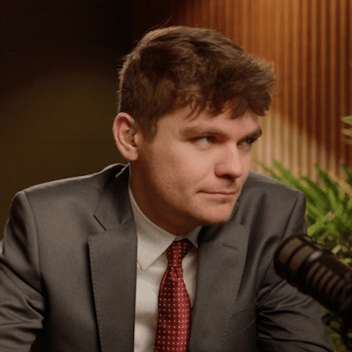 A Man In A Suit And Tie Is Looking At The Camera GIF