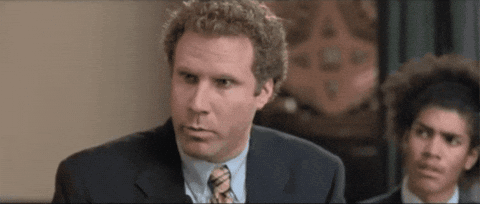A Man In A Suit And Tie Is Looking At The Camera While Another Man Looks On . GIF