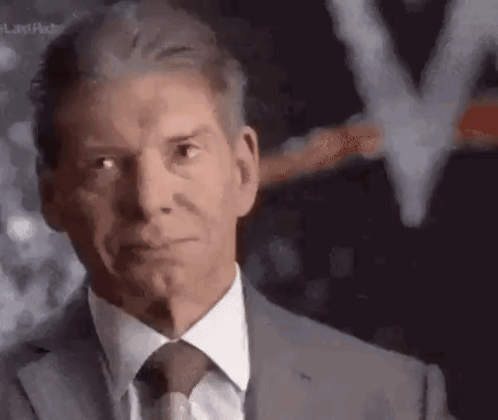 A Man In A Suit And Tie Is Looking At The Camera With A Blurred Background . GIF