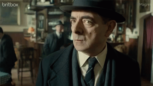 A Man In A Suit And Tie Is Looking At The Camera With A Britbox Logo In The Corner GIF