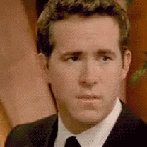 A Man In A Suit And Tie Is Looking At The Camera With A Serious Look On His Face . GIF
