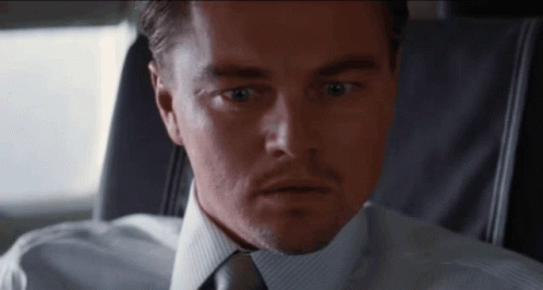 A Man In A Suit And Tie Is Looking At The Camera With A Surprised Look On His Face GIF