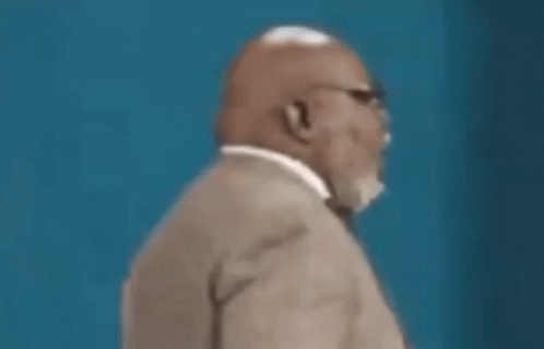 A Man In A Suit And Tie Is Looking Down At Something . GIF