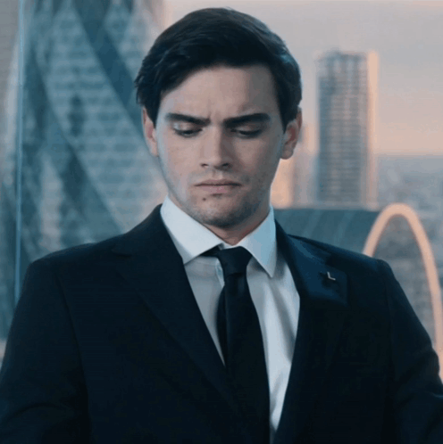 A Man In A Suit And Tie Is Looking Down With A City In The Background GIF