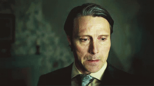 A Man In A Suit And Tie Is Looking Down With His Eyes Closed GIF
