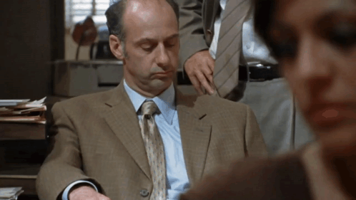 A Man In A Suit And Tie Is Looking Down GIF
