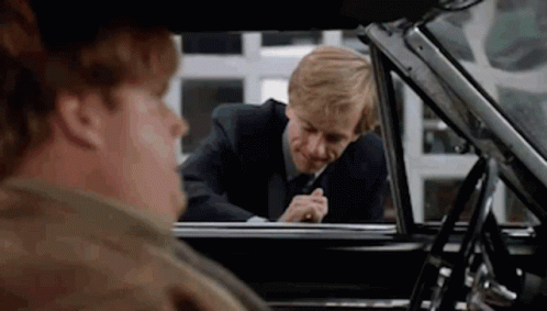 A Man In A Suit And Tie Is Looking Out The Window Of A Car . GIF