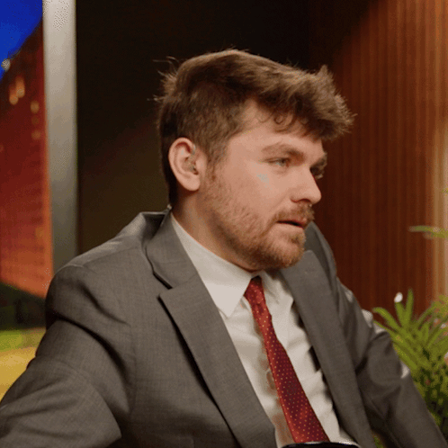 A Man In A Suit And Tie Is Looking To The Side GIF