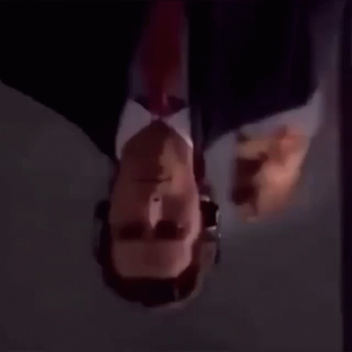 a man in a suit and tie is looking upside down .