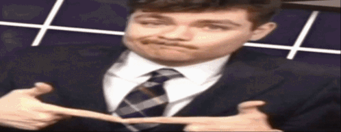 A Man In A Suit And Tie Is Making A Face GIF