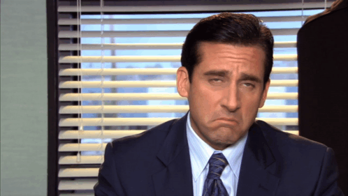 A Man In A Suit And Tie Is Making A Face GIF