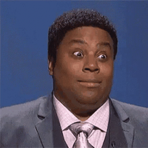 A Man In A Suit And Tie Is Making A Funny Face And Looking At The Camera . GIF