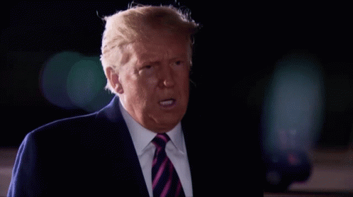 A Man In A Suit And Tie Is Making A Funny Face GIF