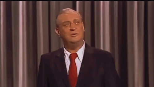A Man In A Suit And Tie Is Making A Funny Face GIF