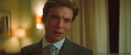 A Man In A Suit And Tie Is Making A Funny Face In A Room . GIF