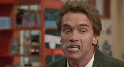 A Man In A Suit And Tie Is Making A Funny Face In A Room . GIF
