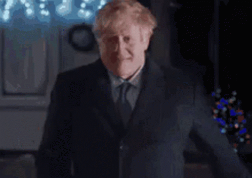 A Man In A Suit And Tie Is Making A Funny Face While Giving A Thumbs Up . GIF