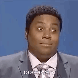 A Man In A Suit And Tie Is Making A Funny Face While Speaking Into A Microphone . GIF