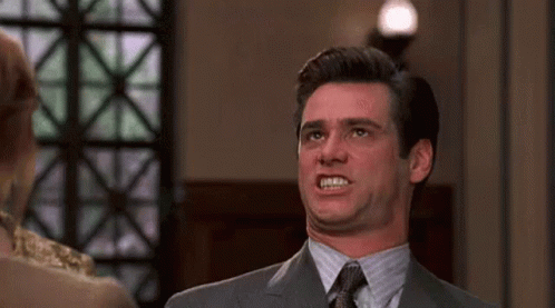 A Man In A Suit And Tie Is Making A Funny Face While Standing Next To A Woman . GIF