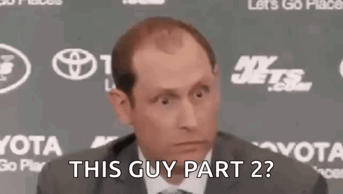 A Man In A Suit And Tie Is Making A Funny Face While Talking To The Camera . GIF