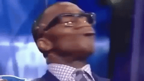A Man In A Suit And Tie Is Making A Funny Face While Wearing Glasses . GIF