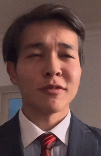 A Man In A Suit And Tie Is Making A Funny Face With His Eyes Closed GIF