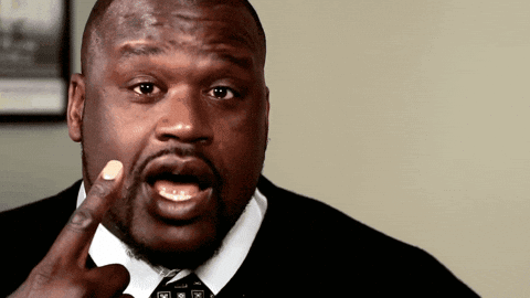 A Man In A Suit And Tie Is Making A Funny Face With His Finger In His Mouth GIF