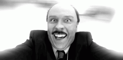 A Man In A Suit And Tie Is Making A Funny Face With His Mouth Open . GIF