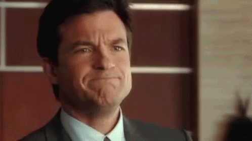 A Man In A Suit And Tie Is Making A Funny Face With His Mouth Open . GIF