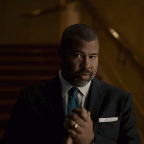 A Man In A Suit And Tie Is Making A Gesture GIF