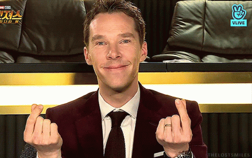 A Man In A Suit And Tie Is Making A Heart With His Hands GIF