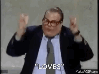 A Man In A Suit And Tie Is Making A Peace Sign With His Hands In The Air . GIF