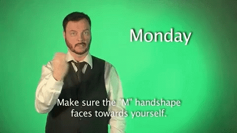 A Man In A Suit And Tie Is Making A Sign That Says Monday Make Sure The M Handshape Faces Towards Yourself GIF