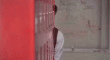 A Man In A Suit And Tie Is Peeking Out From Behind A Red Wall And Says " You Good " GIF