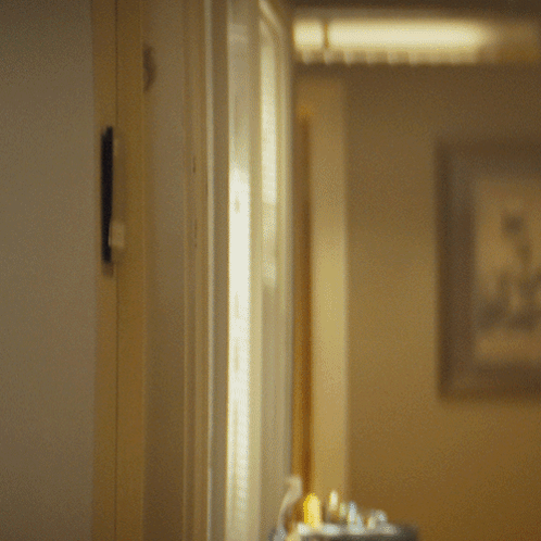 A Man In A Suit And Tie Is Peeking Through A Door GIF