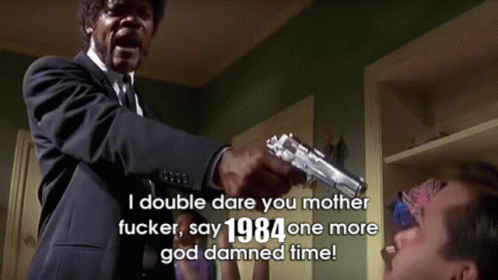 A Man In A Suit And Tie Is Pointing A Gun At Another Man With The Words " I Double Dare You Mother Fucker " Above Him GIF