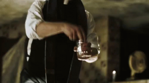 A Man In A Suit And Tie Is Pouring A Drink Into A Glass . GIF