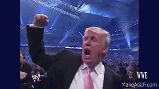 A Man In A Suit And Tie Is Raising His Fist In The Air GIF
