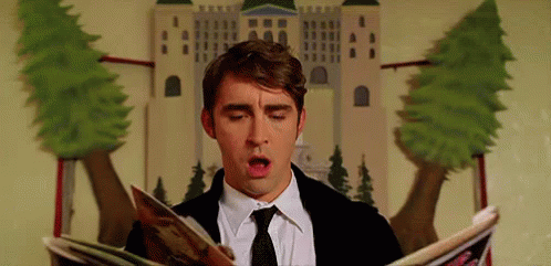a man in a suit and tie is reading a magazine while sitting in front of a castle .