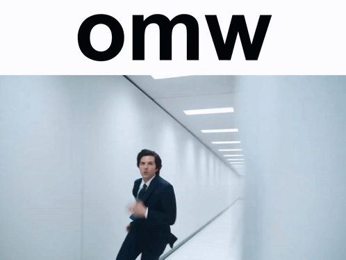 A Man In A Suit And Tie Is Running Down A Hallway With The Word Omw On The Bottom GIF