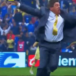 a man in a suit and tie is running on a field in front of a sign that says ien