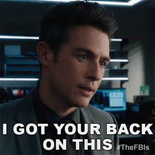A Man In A Suit And Tie Is Saying I Got Your Back On This GIF