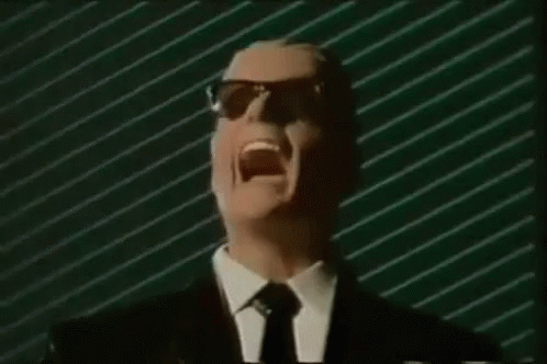 A Man In A Suit And Tie Is Screaming In Front Of A Green Striped Wall . GIF