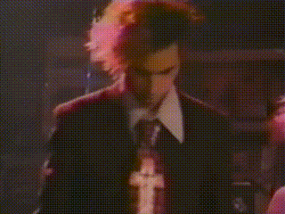 a man in a suit and tie is singing into a microphone in a dark room
