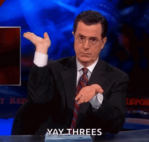 A Man In A Suit And Tie Is Sitting At A Desk And Making A Funny Face While Saying Yay Threes . GIF