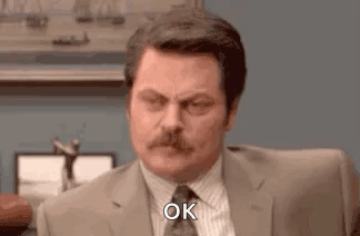 A Man In A Suit And Tie Is Sitting At A Desk And Making An Ok Sign . GIF